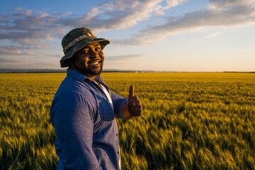 Farmer is standing in his growing wheat field. He is satisfied after successful sowing.