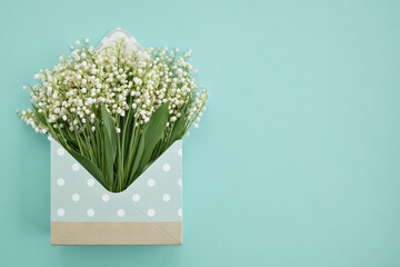 Open envelope with lilies of the valley on a turquoise background. Copy space.
