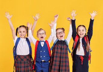 Happy schoolkids with arms raised