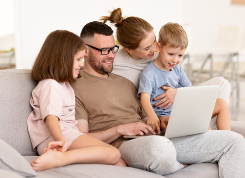 Young beautiful family using modern technologies while spending time together at home