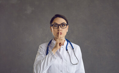 Female healthcare professional or doctor puts her index finger to her lips demanding silence....