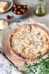Homemade pizza with chicken and cheese on white sauce, light concrete background.