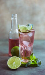 A fresh pink cocktail or mocktail drink with lime, pink grapefruit juice and mint, green background. Paloma.