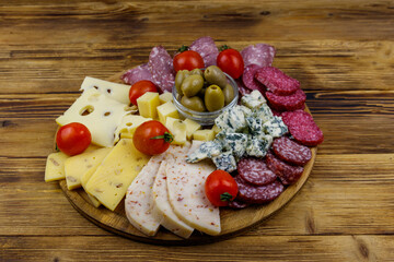 Antipasti platter with olives, cherry tomatoes, assortment of italian salami and cheese on a wooden table