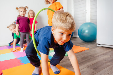 Curly girl crawling on colorful floor through hula hoops