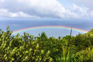 Colorful rainbow over Praslin Island with tropical rainforest around, azure ocean seen from Mont...