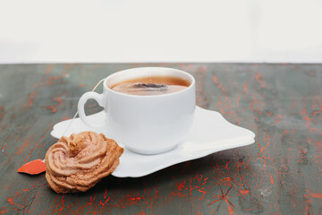 White cup of fragrant tea on a black and red background and a slice of macaroons, a tea bag with an empty red label.