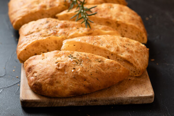 Sliced bread Ciabatta and rosemary on wooden board