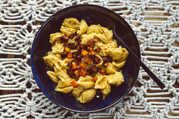 vegan creamy pumpkin pasta with roasted pumpkin cubes as topping, healthy plant-based food