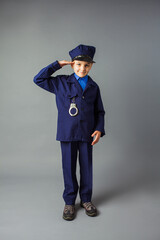 The little boy stand in a police costume and saluted