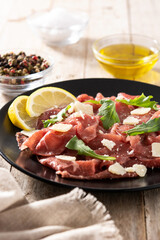 Marbled beef carpaccio on black plate and rustic wooden table. 