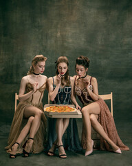 Pretty women in vintage 20s dresses. Young girls in art action sitting together and posing on wall...