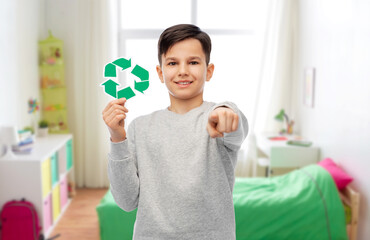 eco living, environment and sustainability concept - smiling boy holding green recycling sign and pointing to camera over white background