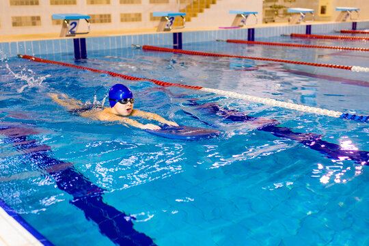 Down syndrome in swimming cap training in seimming pool sport club with trainer
