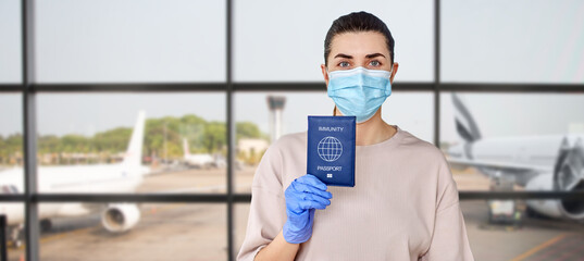 Fototapeta na wymiar health protection, vaccination and pandemic concept - close up of young woman in medical mask and gloves holding immunity passport over airport background