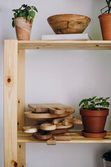 wooden cutting boards lie on the shelf of a wooden shelf. filled shelves of pine wood shelf near white wall.