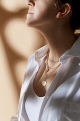 beauty, fashion and jewelry trends concept - close up of woman in white shirt with golden necklace...