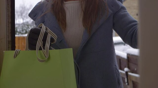 Door opening to woman with gift shopping bag