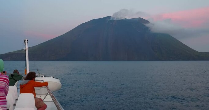 Stromboli, Italy - June 9, 2021: tourists watch from a boat the volcano Stromboli in perennial eruptive activity. Aeolian Islands, Sicily - Italy