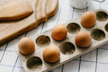 wooden cutting board and eggs in a wooden stand in the kitchen on the table in a rustic house in retro style