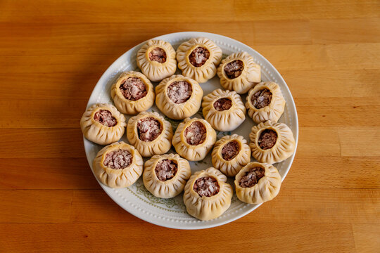 Steamed national Mongolian food dumpling Buuz filled with minced beef, white plate, wooden table, Close up east Siberian Buryats dish poses, Juicy minced meat wrapped handmade dough shirt buuza