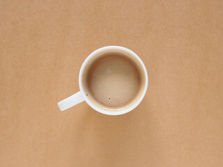 Top view, flat lay hot coffee in white mug on brown desktop workpleace. Copy space for your text..