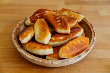 Delicious little fried pies with green onion and egg, patties or pirozhki, Traditional Russian pastry cuisine, Homemade cakes, white plate on wooden background, Food Slavonic concept rustic village