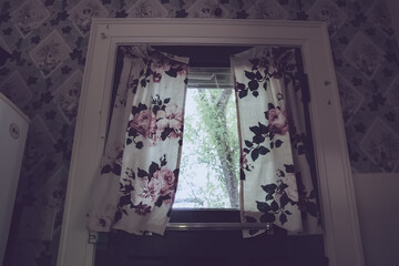 Flower-patterned wall and curtain with bright window in kitchen