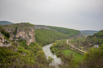 Fototapeta na wymiar Iskar river gorge from above near Karlukovo, Bulgaria. Rail road, moody day panoramic high angle elevated view