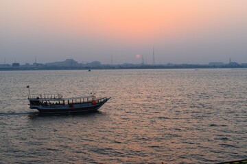 Fototapeta premium Beautiful tranquil scene of a dhow boat on the calm sea in Doha, Qatar, at sunset.