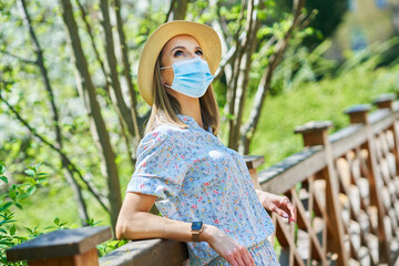 Obraz premium Woman in mask wearing hat in the park.