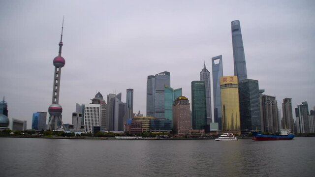 View on Shanghai Skyline over the Bund river with big boat driving over the river on cloudy day