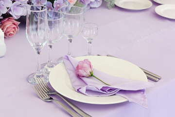 Setting the table for the celebration. A white plate with a lilac napkin on the table