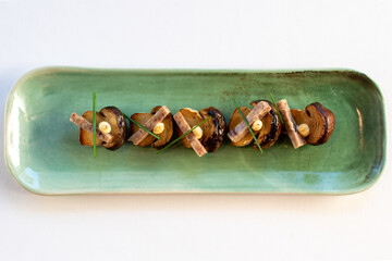 Top view of grilled porcini mushrooms with pork strips and garlic mayonnaise.