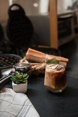iced coffee in iridescent stemless glass served on black table at cafe​