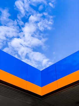 Geometric corner in orange and blue over a blue sky with sparse white fluffy clouds
