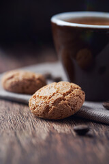 Amaretti (Italian biscuits) and a cup of coffee on dark wooden background. Close up. 