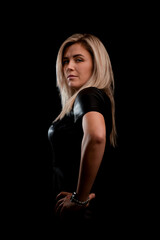 Naklejka premium A beautiful blonde girl with long hair looks at the camera on a black background. Taken from the side