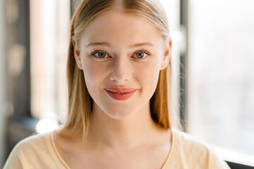 Young blonde white woman smiling and looking at camera indoors