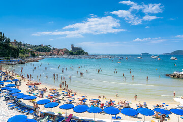 crowded beach on the Ligurian Sea, Lerici , Italy with blue umbrellas - 439820915
