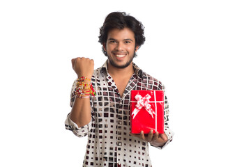 Man or Brother showing rakhi on his hand with shopping bags and gift box on the occasion of Raksha Bandhan festival.