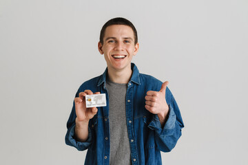 Young brunette white man gesturing while posing with credit card