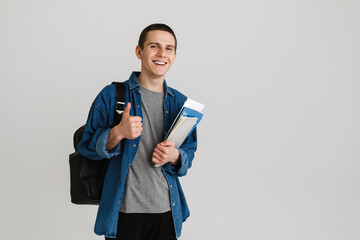 Young student man gesturing thumb up while holding exercise books - Powered by Adobe