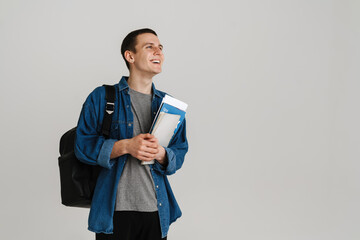 Young brunette student man smiling while holding exercise books