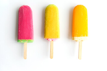 Three ice creams of different colors lie in a row on a white background. Summer refreshing dessert.