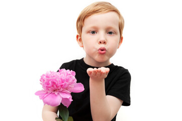 Little cute child holding a pink peony flower and sending an airkiss. Adorable stylish boy  isolated on white background. Love and romantic concept