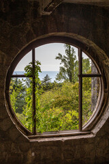 round window in an abandoned estate overlooking the sea