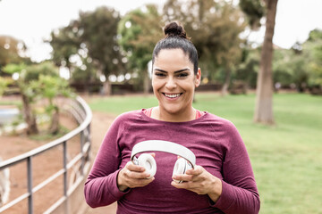 Curvy woman listening playlist music after jogging routine outdoors - Focus on face