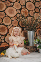 Child Girl wearing bunny ears and sitting with white rabbit on the wooden background.