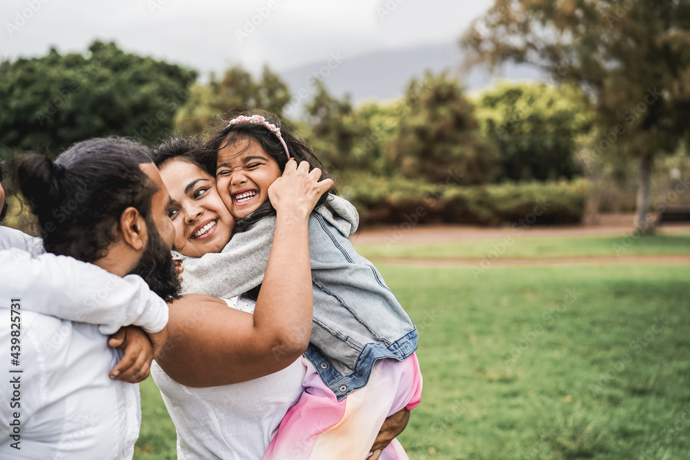 Poster happy indian family having fun outdoor at city park - main focus on girl face